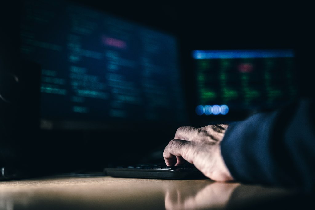 A person typing on a computer in the dark.