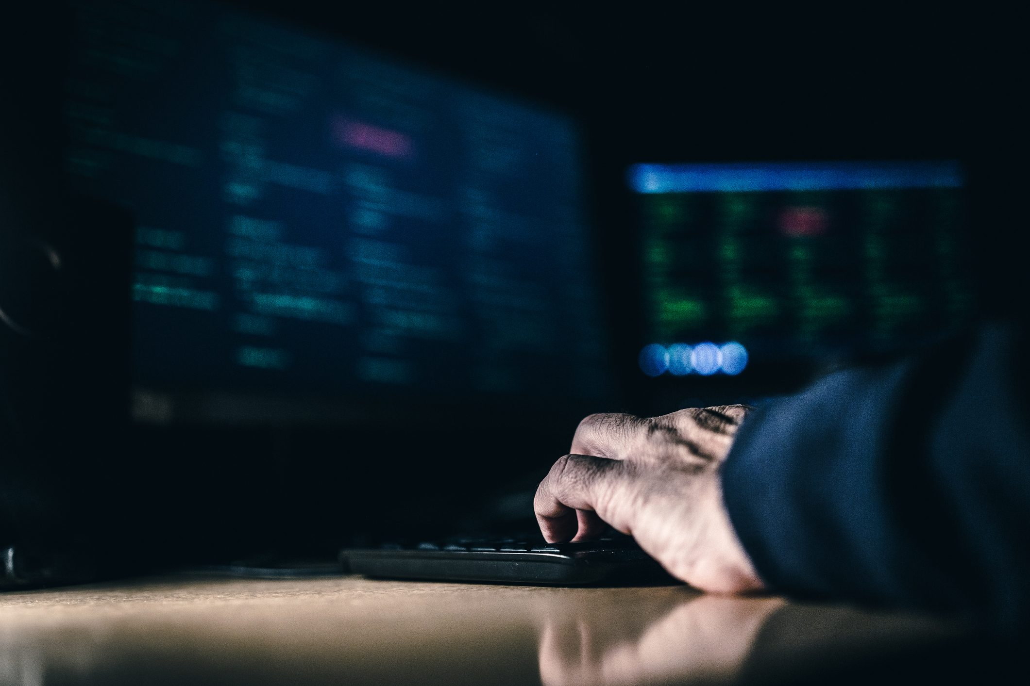 A person typing on a computer in the dark.