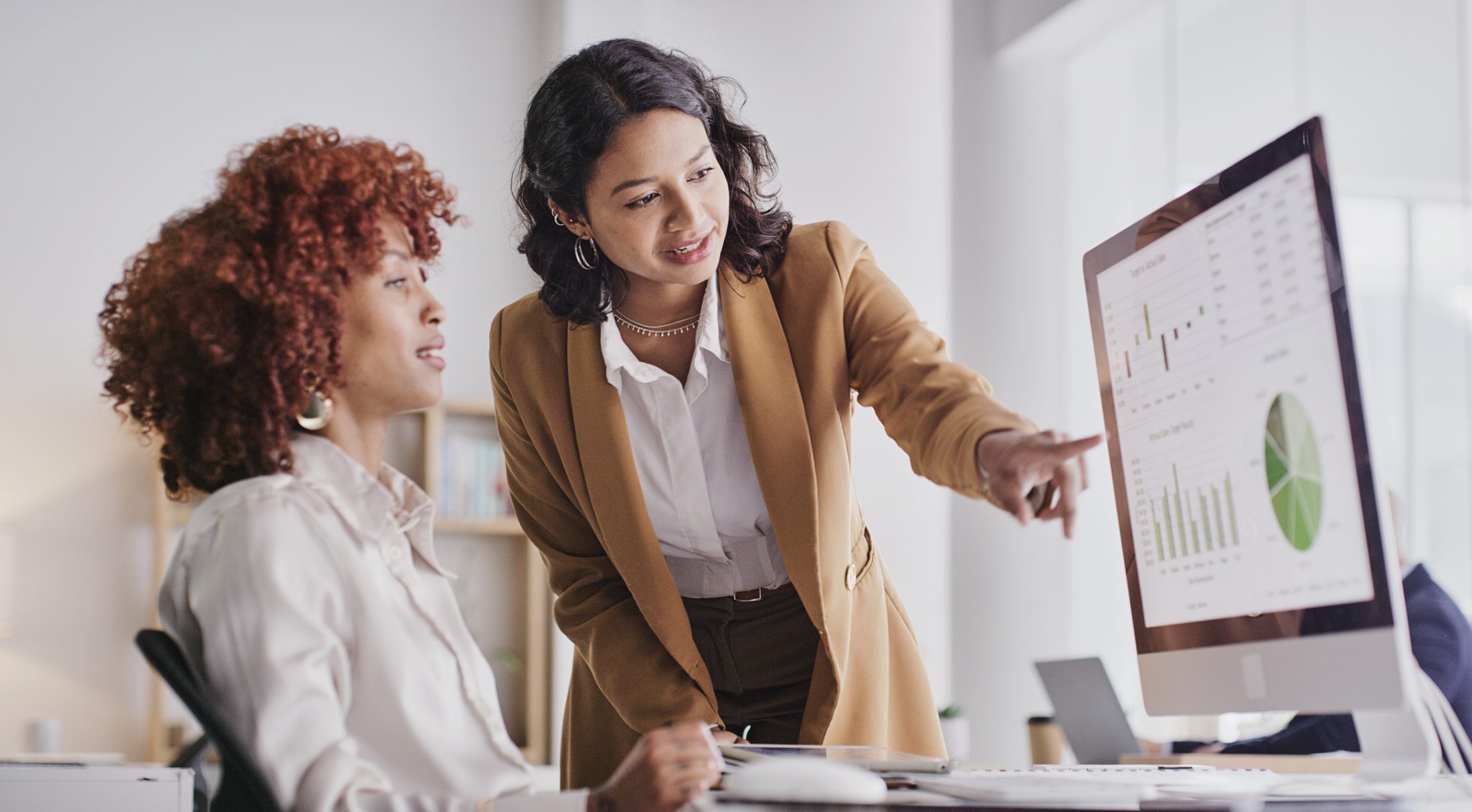 A woman showing something on a computer to another woman.