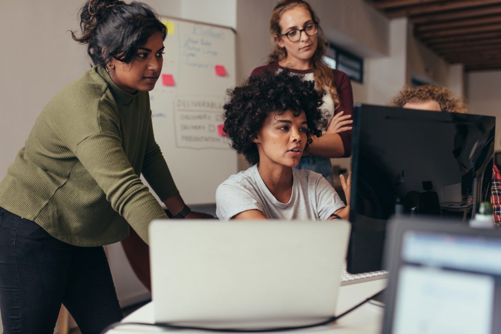 A group of people working on a computer in an office.