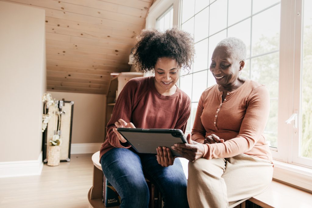 Two women looking at a tablet computer in their home.