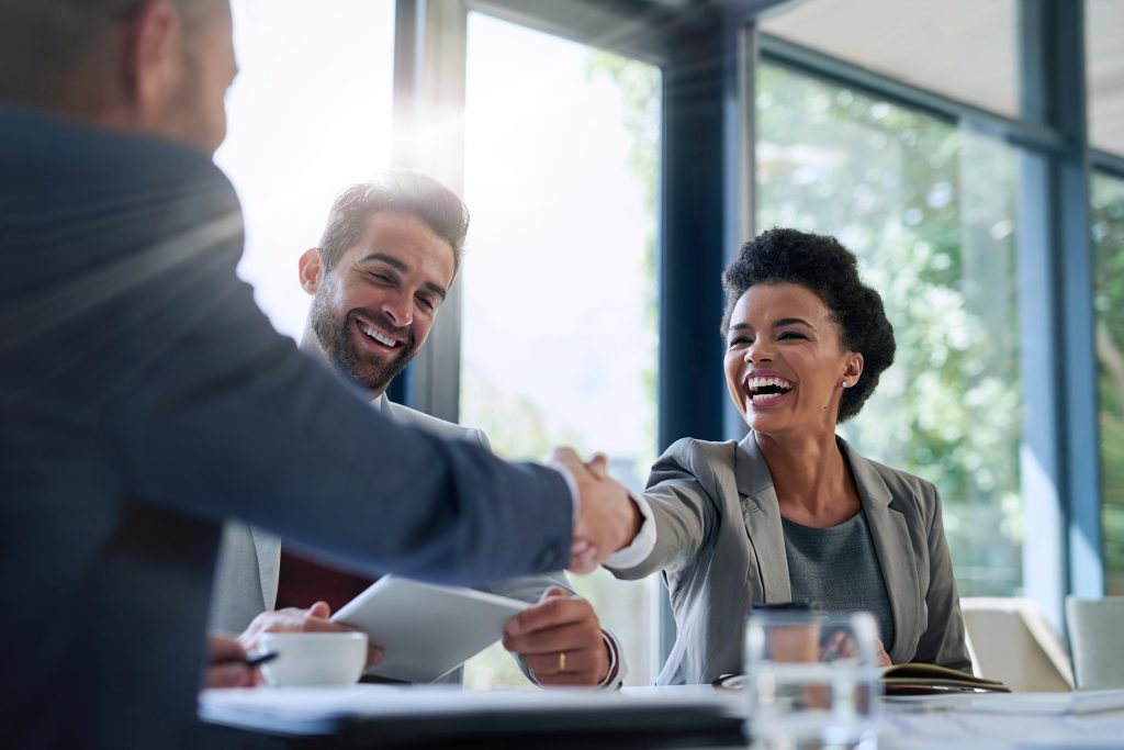 Two business people shaking hands at a meeting.