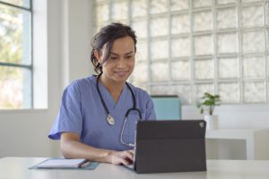Une infirmière utilise une tablette électronique dans son bureau.