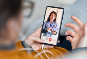 A woman is using a smartphone to video chat with a doctor.