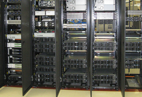 Rows of open server racks filled with various data storage and network equipment in a well-lit data center.