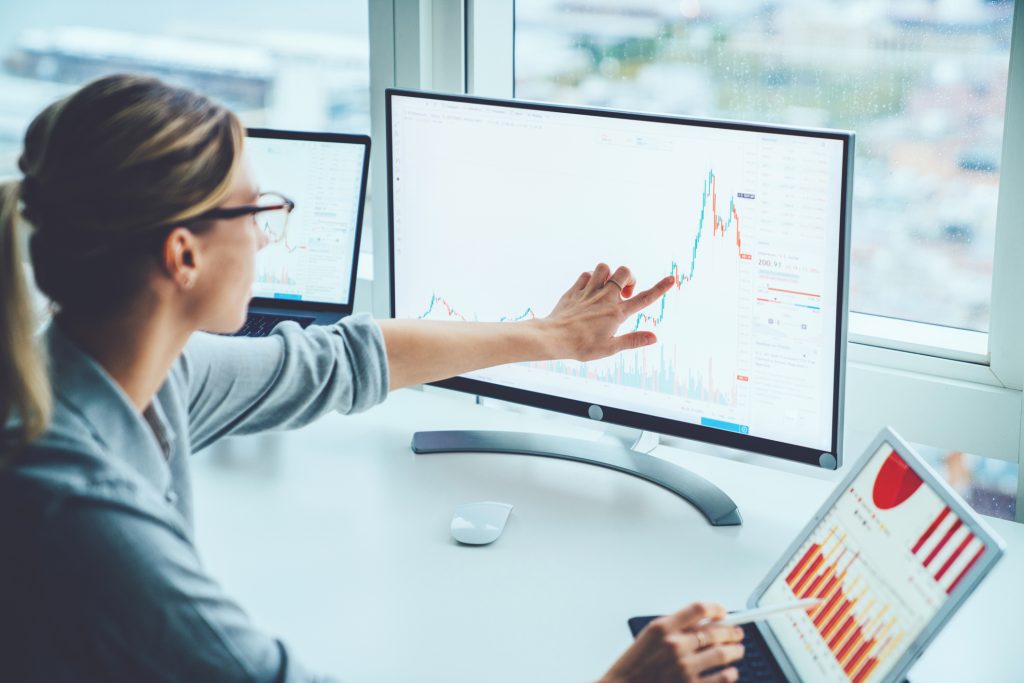 A woman is pointing at a graph on a computer screen.