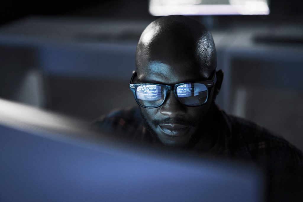 A man wearing glasses is sitting in front of a computer.