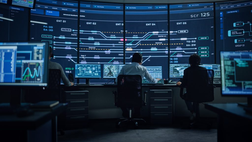 A group of people sitting at a desk with multiple screens.