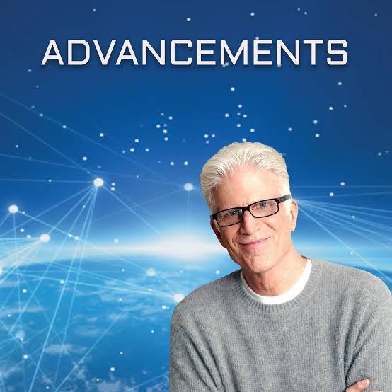 A man in glasses and a gray sweater stands in front of a blue, futuristic background with the word "ADVANCEMENTS" above him.